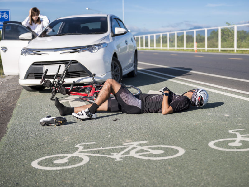 A cyclist on the ground after getting hit by a car.