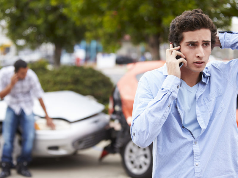 A young man on the phone after a car accident.