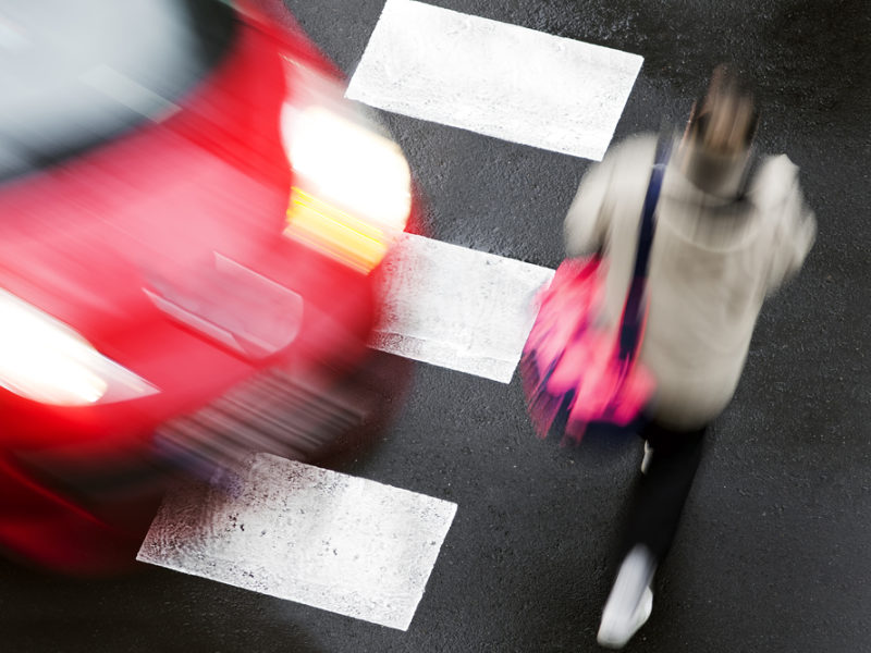 A pedestrian crossing the street about to get hit by a car.