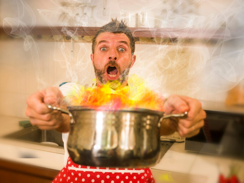 Chef holding a metallic pot which has caught on fire